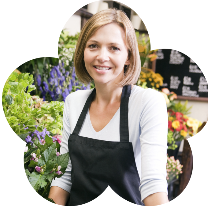 Paula steht vor ihrer Auswahl an Blumen und lächelt in die Kamera.